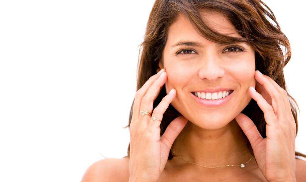 Woman giving a face massager to herself - isolated over white